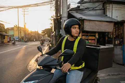A delivery rider on his scooter at a barangay corner at sunrise