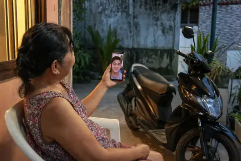 A mother shows the new scooter to her son on a video call